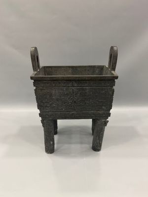 une vieille jardinière en métal posée sur une table blanche