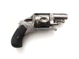 un revolver argenté avec une poignée noire sur une surface blanche