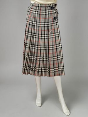 a woman wearing a skirt and sweater with a plaid pattern on it