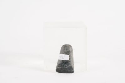 a black rock in a clear glass container on a white surface