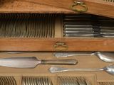 a lot of silverware in a wooden box on a table