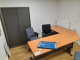 a desk with a laptop and a chair in a room