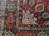 a close up of a red and blue oriental rug on a wooden floor