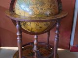 un vieux globe terrestre posé sur un socle au sol