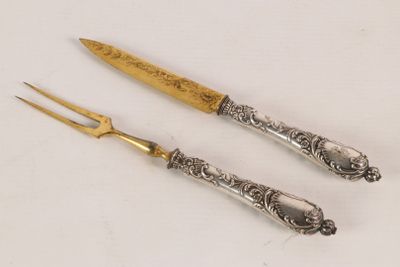 pair of silver plated knives with a gold handle on a white surface