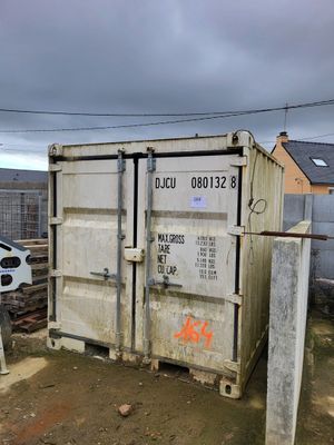 a white container sitting in the dirt next to a fence