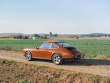 an orange car is parked on a dirt road near a field