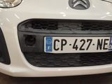 the front of a white car with a number plate on it