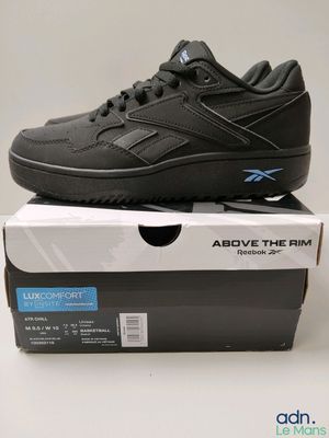 la boîte d'une paire de chaussures noires est posée sur une surface blanche