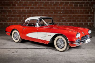 an old red and white car parked in front of a brick wall
