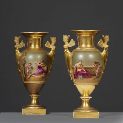 two gold vases with paintings on them sitting on a table