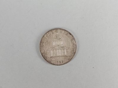a close up of a coin on a white surface with a building in the background