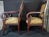 two wooden chairs with yellow upholstered cushions sit in front of a fireplace