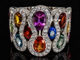 a close up of a ring with multi colored stones on a black surface