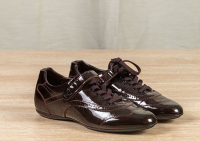 pair of brown shoes on a wooden table with a curtain in the background