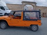 une jeep orange garée sur un parking, avec un camion en arrière-plan