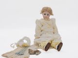 a doll that is sitting on the ground next to a bag