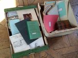 two open boxes with books and papers in them on the floor