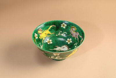 un bol vert orné d'un motif représentant des animaux et des fleurs