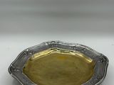 a silver plate with a gold rim on a white surface