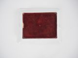 an empty red plate on a white surface with a small piece of food in it