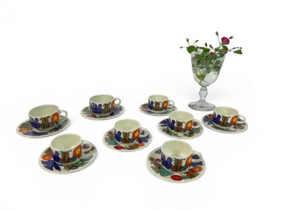 six cups and saucers with a vase of flowers in the background