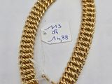 a close up of a gold chain bracelet on a white surface