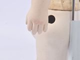 a small doll that is standing on a white surface