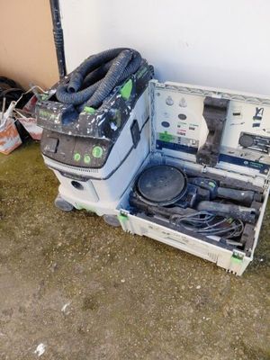 une boîte contenant un aspirateur et d'autres objets, posée par terre