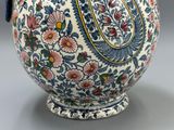 un grand vase avec une anse bleue posé sur une table