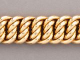 a close up of a gold bracelet on a gray surface