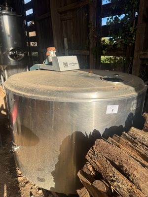 a large metal pot sitting on top of a pile of wood