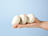 someone holding three macarons in their hand on a blue background