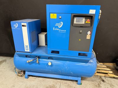un compresseur d'air posé sur une palette en bois, à côté d'une machine bleue