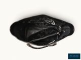 the black purse has a chain around it and is on a white surface