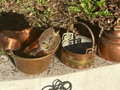 a lot of old copper pots and pans on the ground