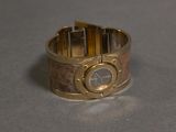 a gold bracelet with a watch on it on a table