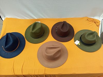 Plusieurs chapeaux sont posés sur une table recouverte d'une nappe jaune.