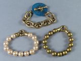 trois bracelets ornés de perles et d'un bouton bleu sur un fond gris