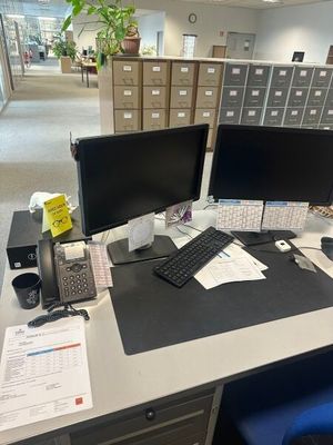 un bureau sur lequel se trouvent deux écrans d'ordinateur et un téléphone