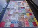 a patchwork rug on the ground next to a car