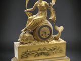 l'image d'une horloge en or sur laquelle est assise une femme