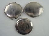 three antique silver pocket watches on a white surface