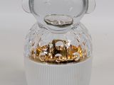 un petit bocal en verre orné d'un motif doré sur le couvercle