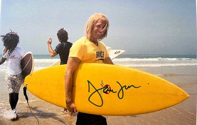 un homme qui tient une planche de surf sur la plage