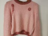 un pull rose suspendu à un cintre accroché au mur devant une porte
