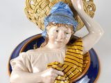une figurine représentant un garçon avec un panier sur la tête