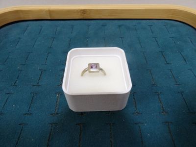 une boîte blanche contenant un anneau, posée sur un tapis bleu