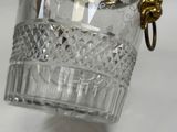 a glass vase with a gold handle on a white table