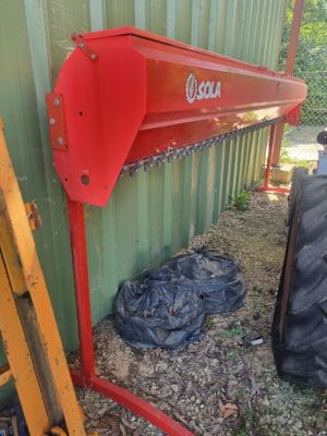 une machine rouge qui se trouve à côté d'un bâtiment vert